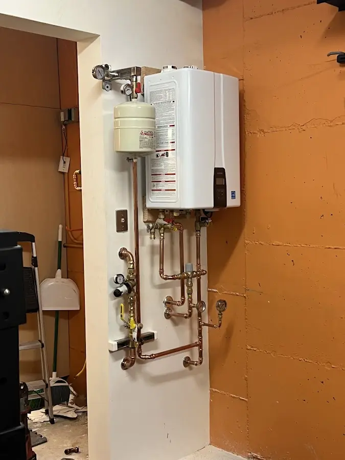 Plumbing technician inspecting water heater connections in Pineville